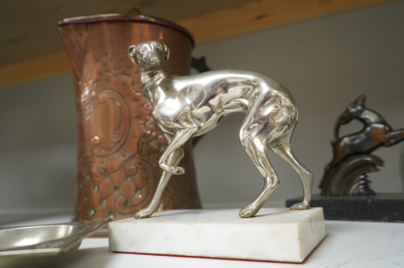 A pair of French Art Deco stag bookends, a chrome Greyhound mounted on a marble base, a large Arts and Crafts copper jug and two other items, jug 27cm high